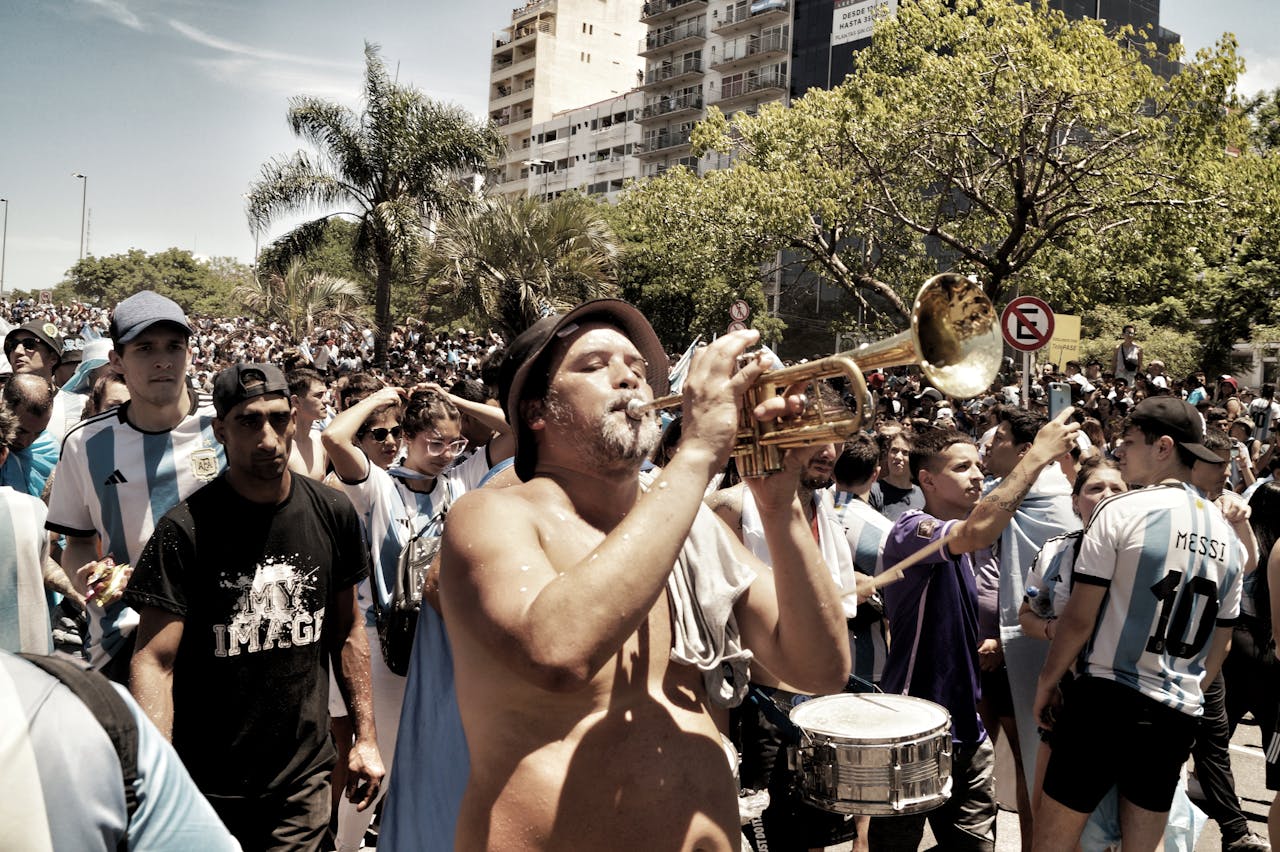 Lively street celebration in Buenos Aires with musicians and a cheering crowd in Argentina jerseys.