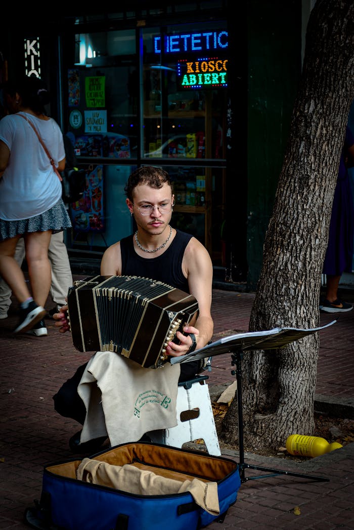 A street musician performs with an accordion on a bustling Buenos Aires sidewalk.